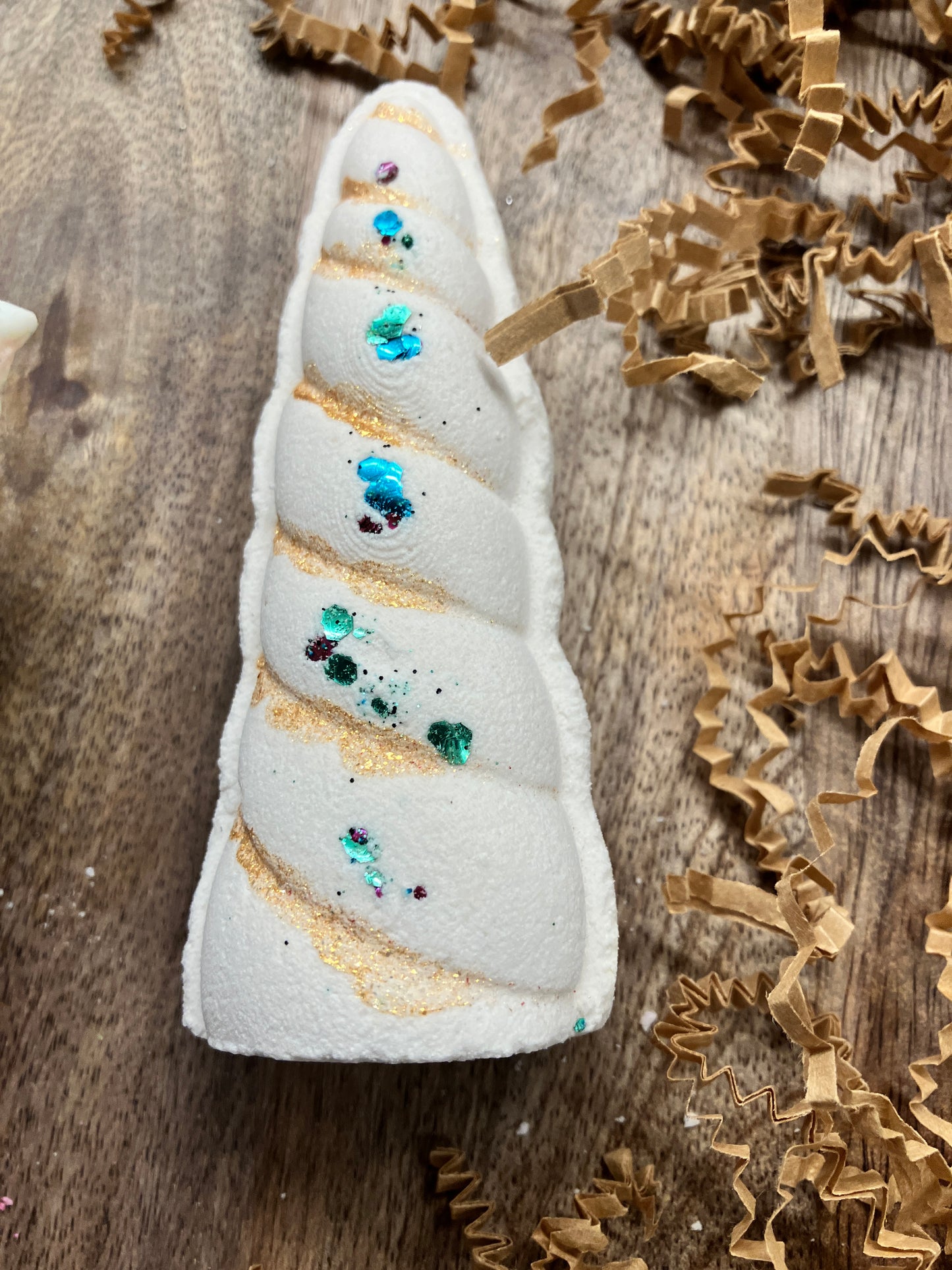 Unicorn horn shaped bath bomb with delicate gold touches and teal/green body safe biodegradable glitter.