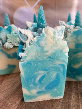 Load image into Gallery viewer, Snowflake the Magical Unicorn Bar front and center zoomed in on single bar of soap. Shows crystal like inside from salt and swirls of light blue teal and white. Frosted blue unicorn horn has a beautiful rough texture like a frosted glass. Ears are white with teal painted insides. Sides of unicorn frosted soap bar top are covered in snowflake imbeds.
