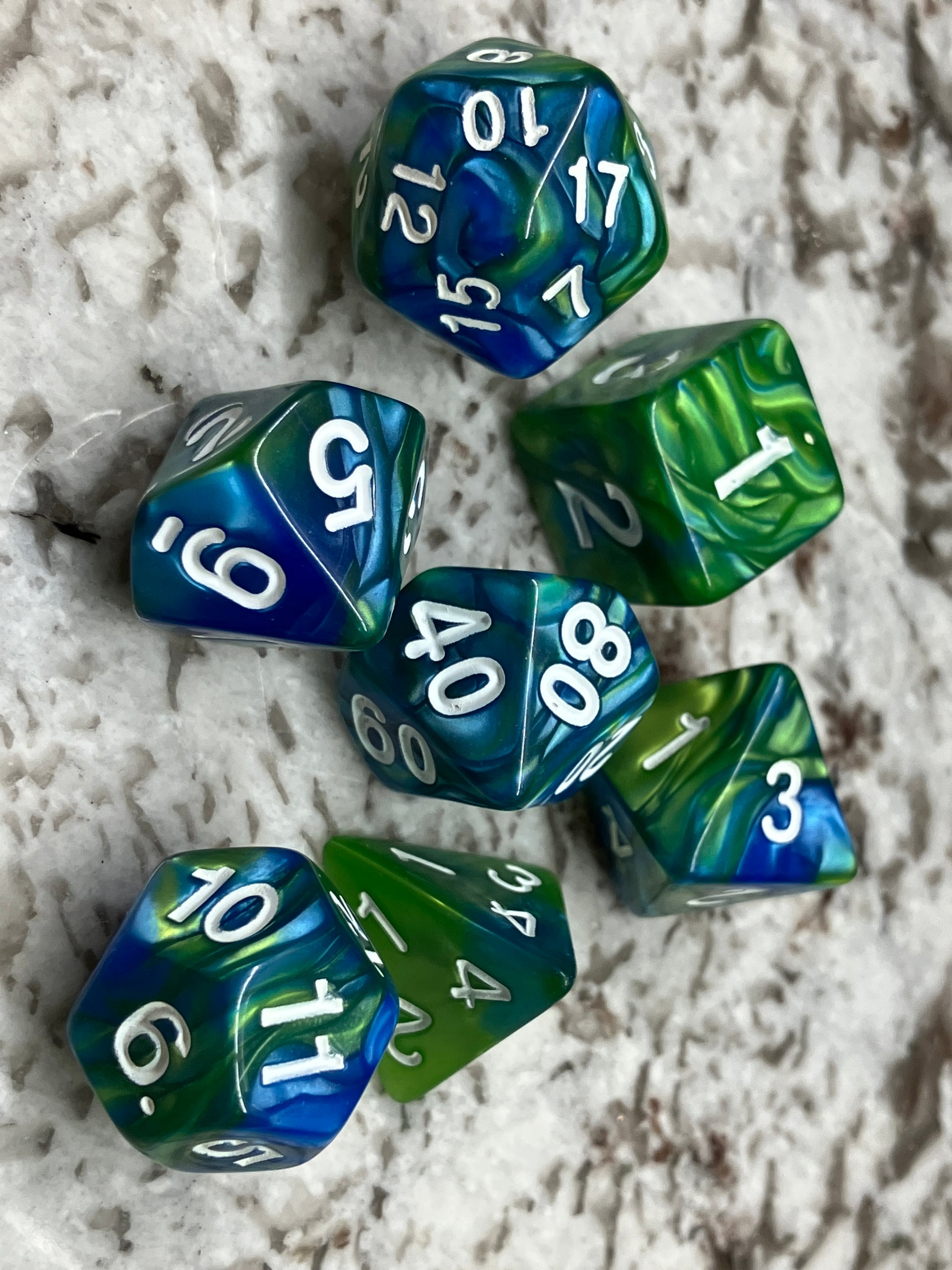 Set of seven dice for role play gaming. Shown in marine blue and lime green.