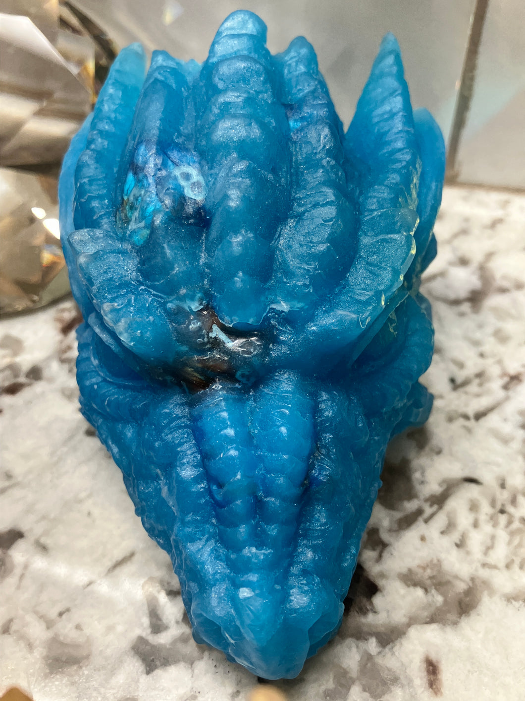 Vibrant blue dragon head shown up close can see a bit of the dice inside.