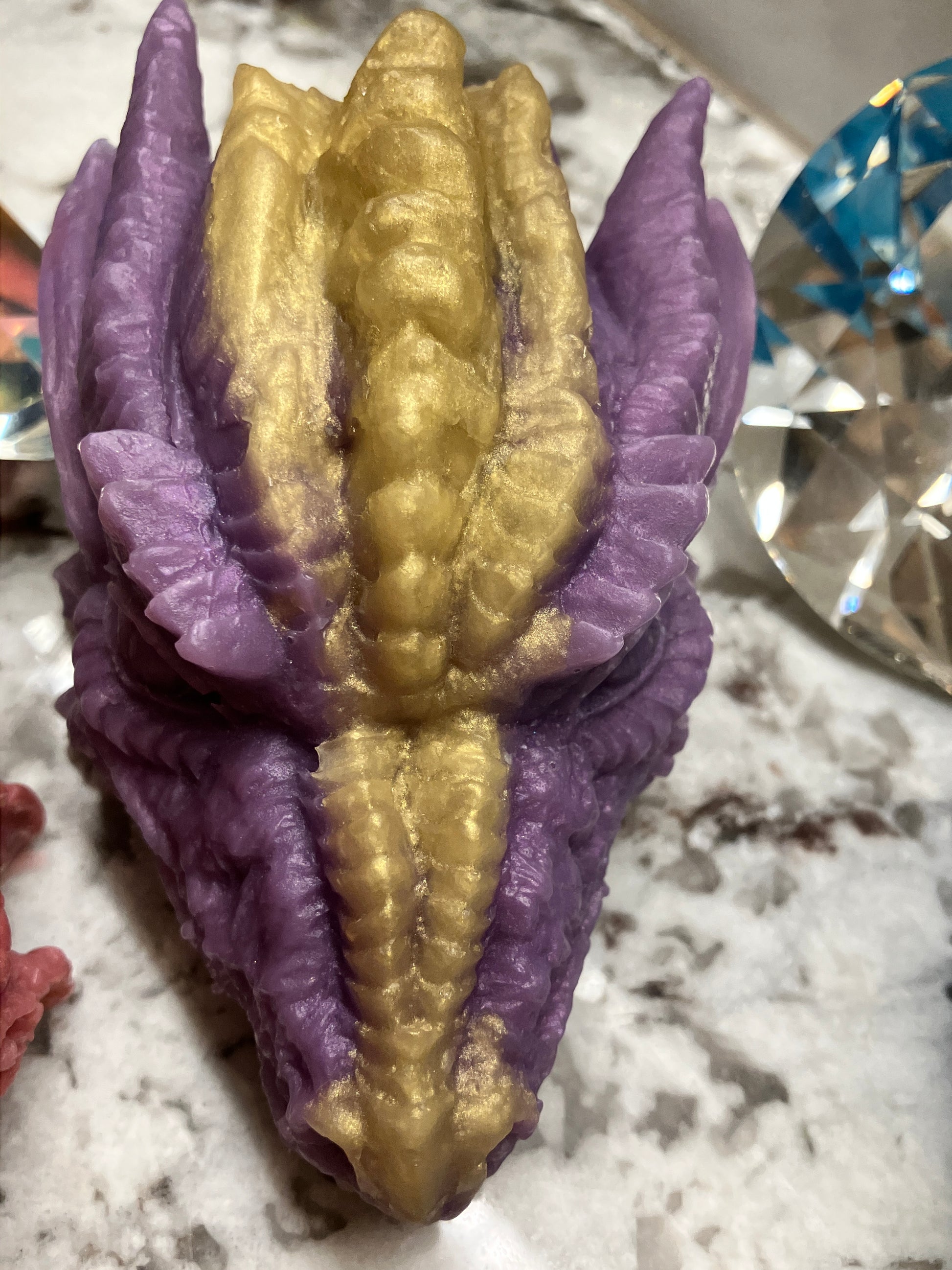 Close up of purple dragon head soap has a gold stripe down the center of his head.