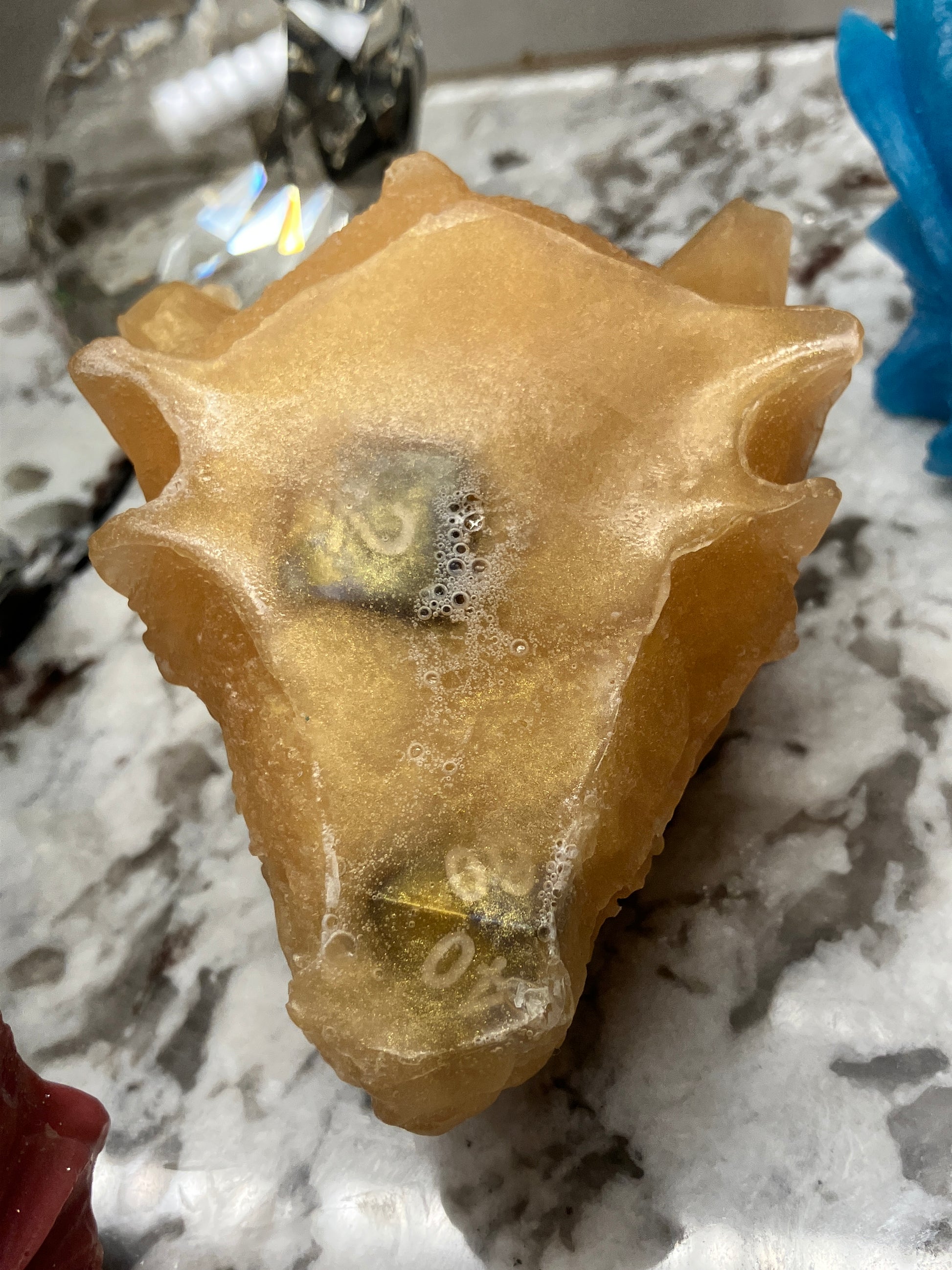Zoomed in bottom of the gold dragon head soap showing the dice are molded inside the soap.