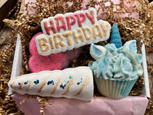 Load image into Gallery viewer, The products described previously are all arranged inside a box and cushioned with brown shred. They are arranged in the following order: The &quot;Happy Birthday&quot; bath bomb  is on top of the playful pink and purple cloud and above the magical unicorn. The soap unicorn is on the far right of the box, beside the playful pink cloud and elegant unicorn horn bath bombs. The elegant unicorn horn is in the far right hand corner of the box with the playful pink and purple cloud above it.
