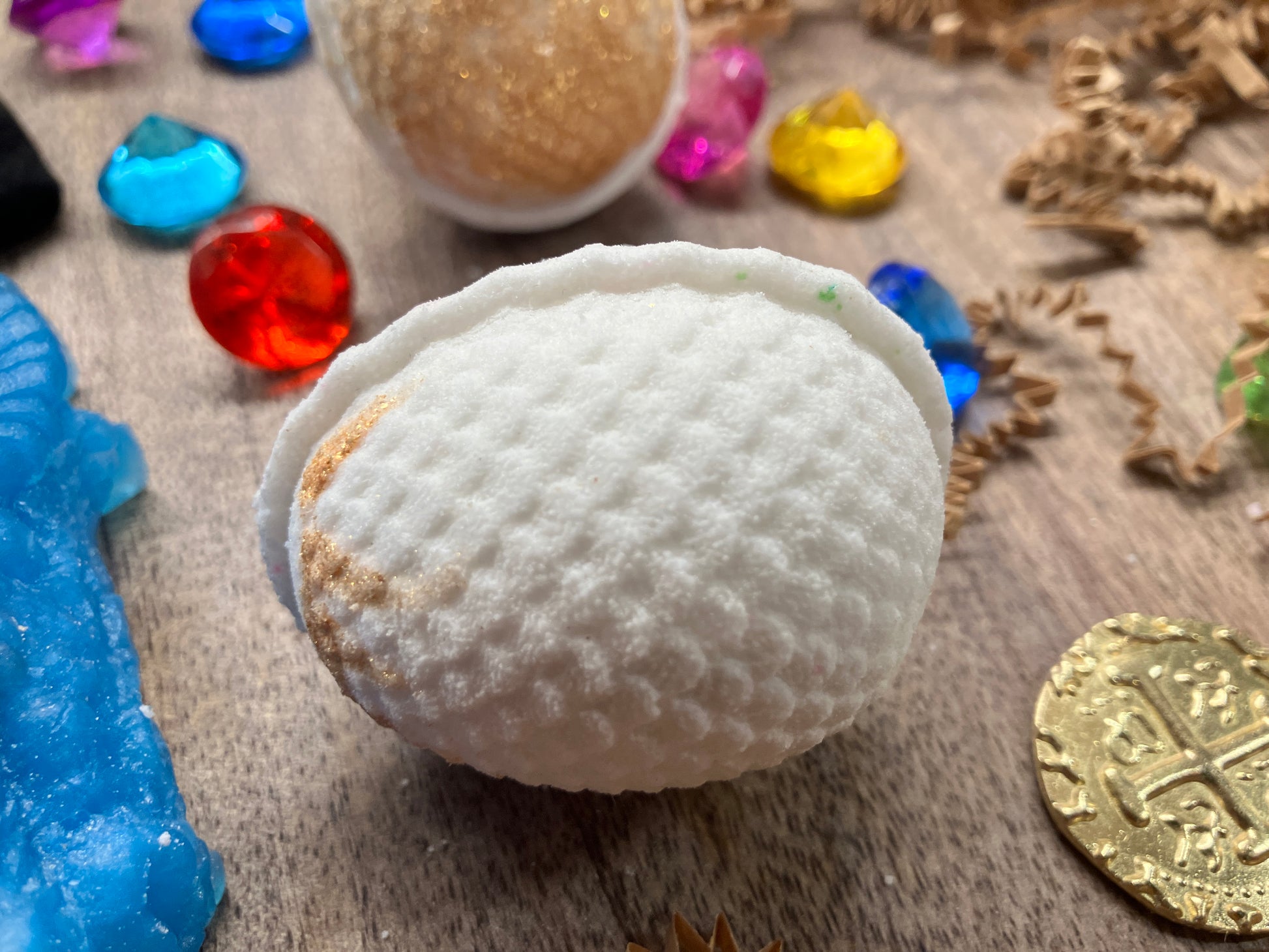 White dragon egg bath bomb with gold brushing on top.
